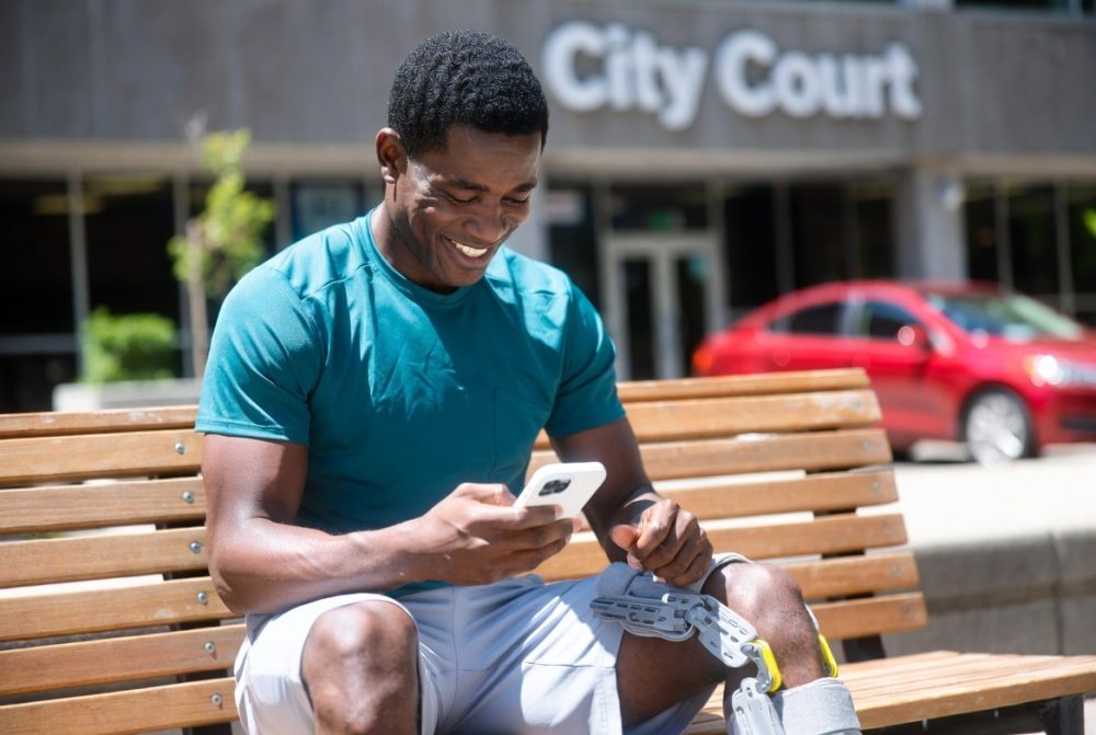man smiling in front of court and his car